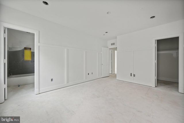 unfurnished bedroom with visible vents, a decorative wall, and ensuite bathroom