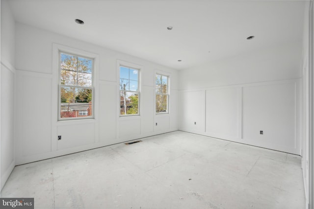 empty room featuring a wainscoted wall, visible vents, and a decorative wall