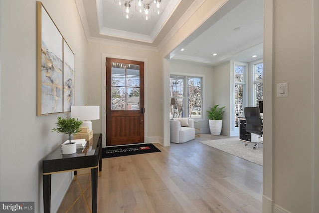 foyer entrance with baseboards, a raised ceiling, ornamental molding, wood finished floors, and recessed lighting