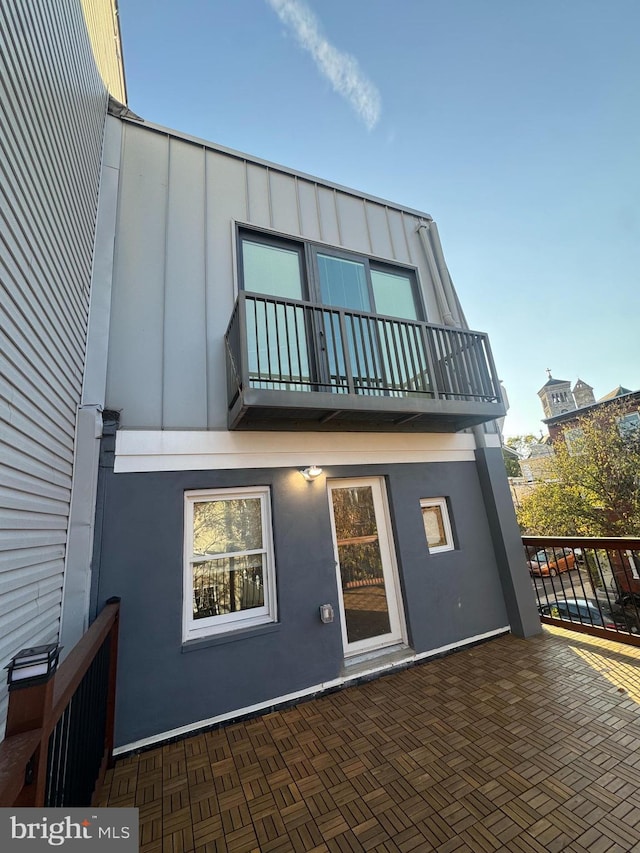 back of property featuring a patio, a balcony, board and batten siding, and stucco siding