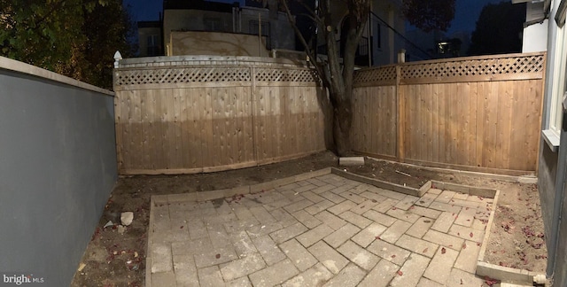 patio at twilight featuring a fenced backyard