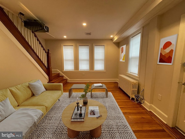 living room with visible vents, radiator, stairs, recessed lighting, and wood finished floors