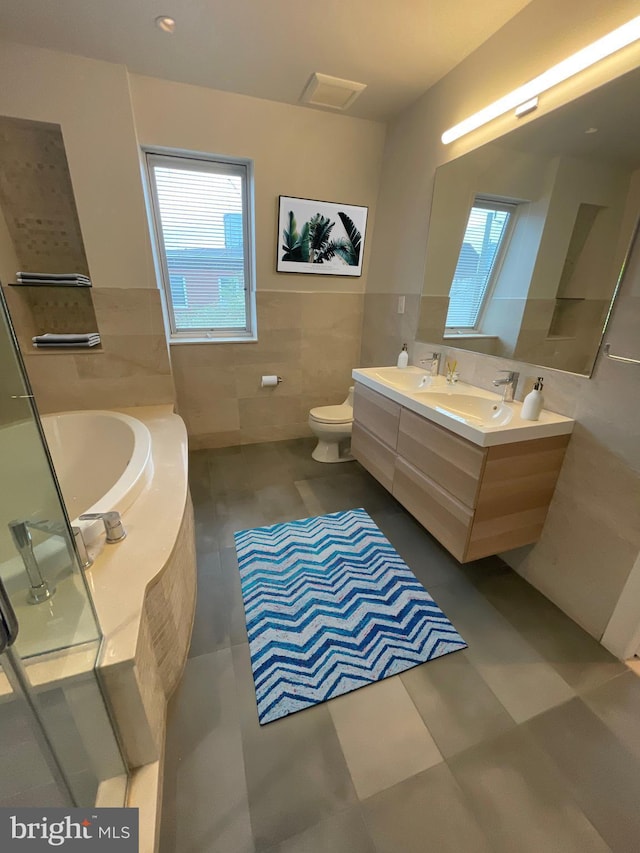 full bath with a sink, plenty of natural light, toilet, and tile walls