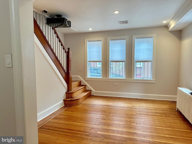 interior space featuring stairway, radiator, baseboards, and light wood-type flooring