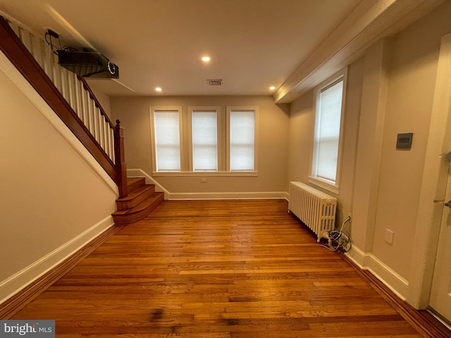 spare room with visible vents, wood finished floors, radiator, baseboards, and stairs