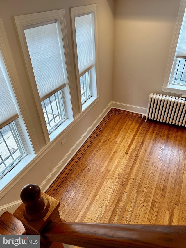 spare room featuring radiator, baseboards, and hardwood / wood-style flooring