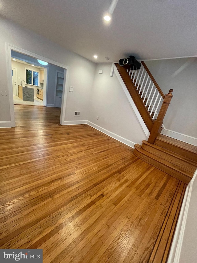 interior space featuring stairway, visible vents, baseboards, and hardwood / wood-style flooring