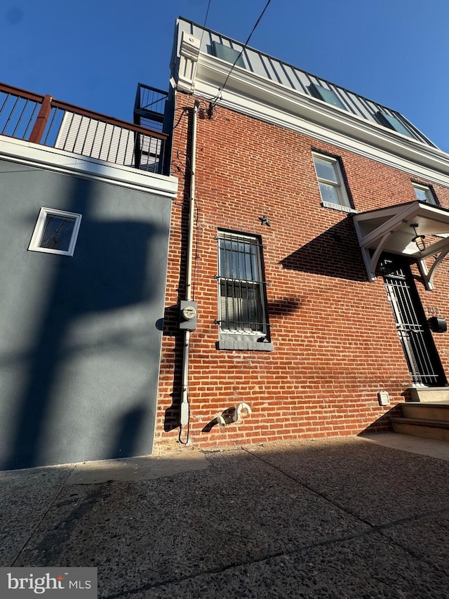 view of side of property featuring a standing seam roof, brick siding, and metal roof