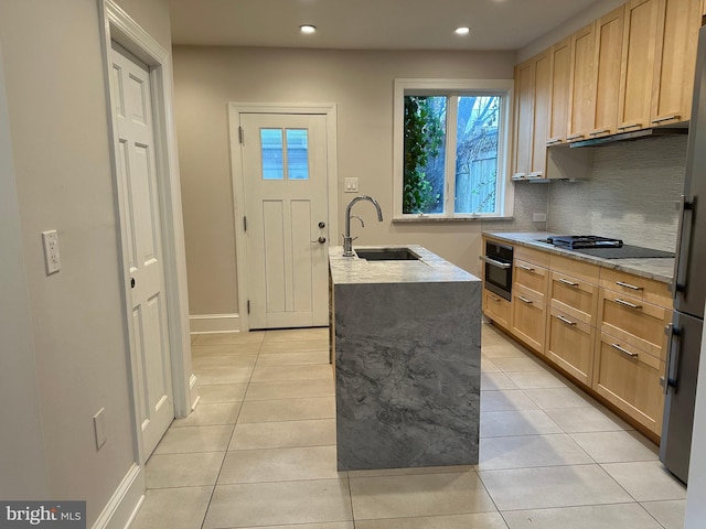 kitchen with oven, gas stovetop, light brown cabinets, and a sink