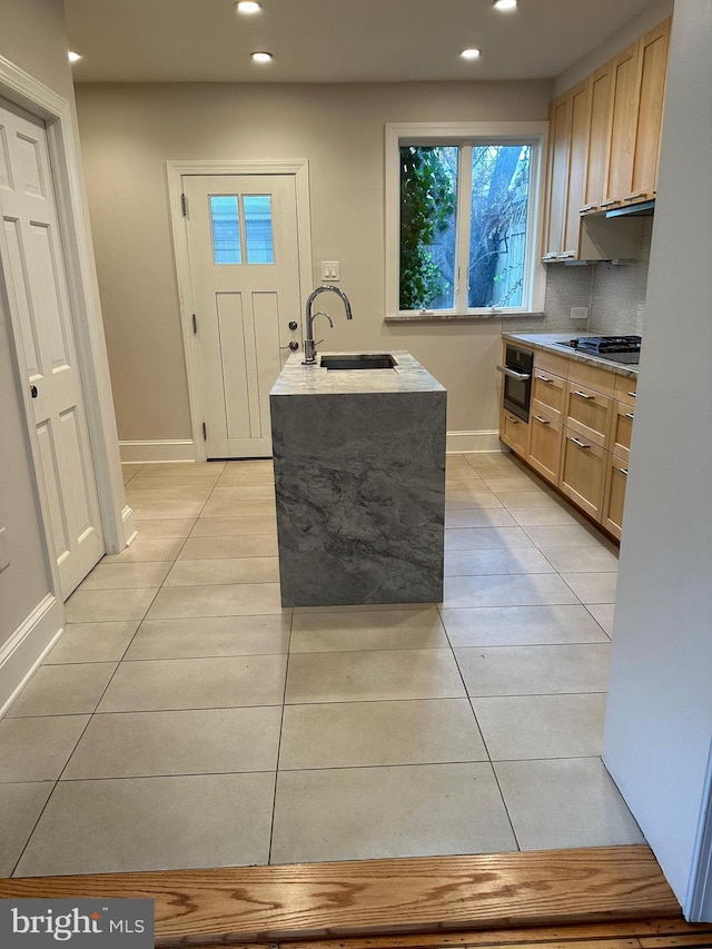 kitchen with light tile patterned floors, gas stovetop, oven, a sink, and light countertops