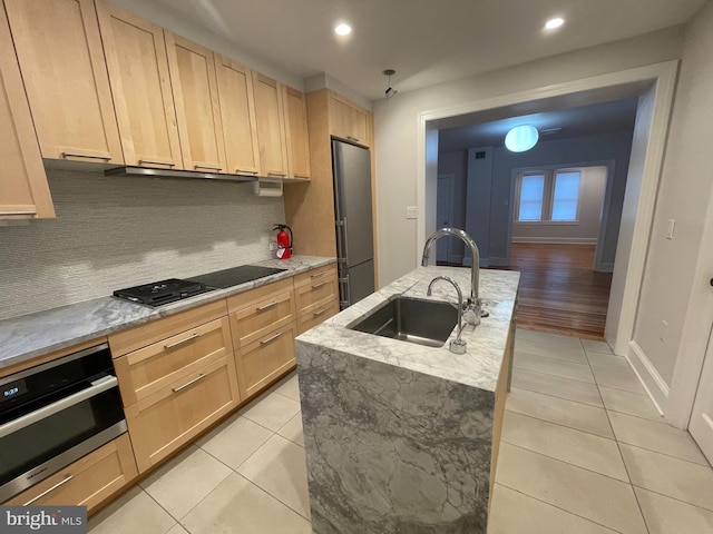 kitchen with a sink, appliances with stainless steel finishes, light tile patterned flooring, and light brown cabinetry