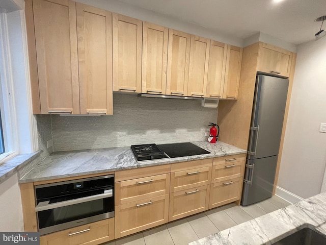 kitchen featuring light stone countertops, backsplash, light brown cabinets, and appliances with stainless steel finishes