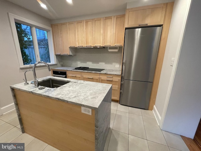 kitchen featuring light brown cabinets, a sink, freestanding refrigerator, black stovetop, and light tile patterned flooring