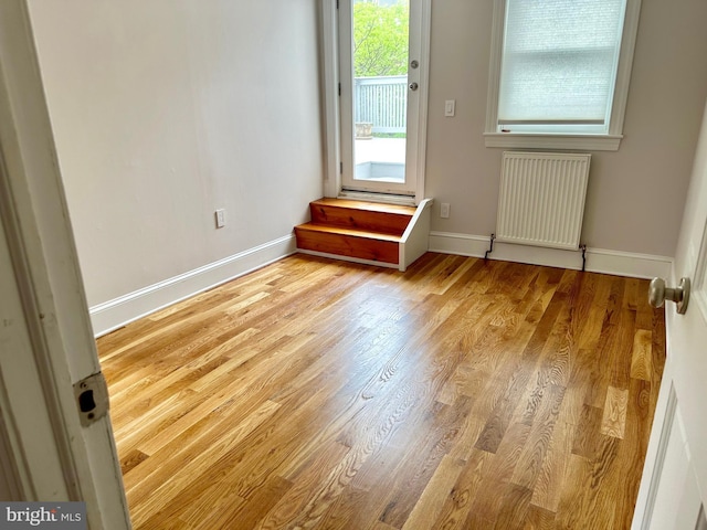 interior space featuring radiator heating unit, wood finished floors, and baseboards