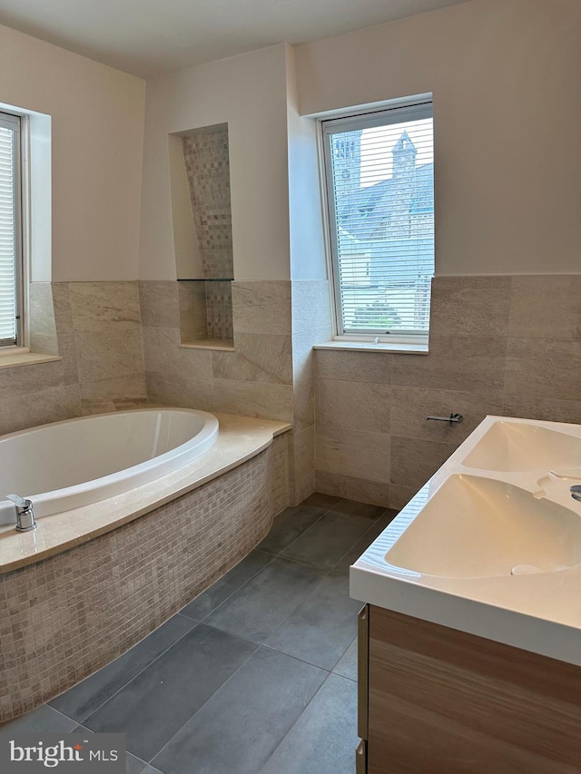 full bathroom featuring vanity, a garden tub, wainscoting, tile patterned floors, and tile walls