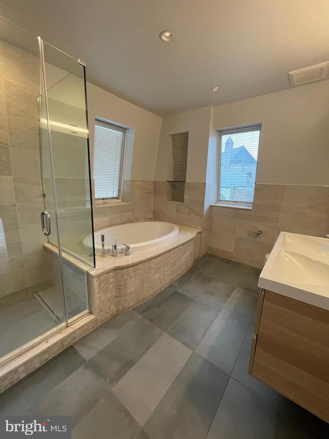 bathroom with visible vents, tile walls, a garden tub, a stall shower, and vanity