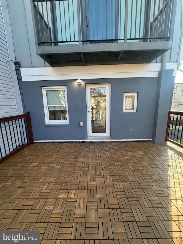 view of exterior entry featuring a balcony and stucco siding