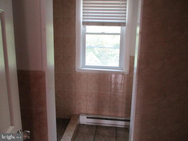 bathroom featuring tile patterned flooring, tile walls, and a baseboard radiator