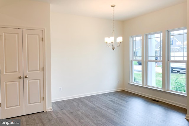 unfurnished room with a chandelier, visible vents, baseboards, and wood finished floors