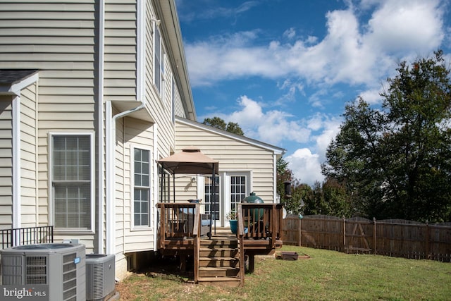 back of house featuring a deck, cooling unit, and a lawn