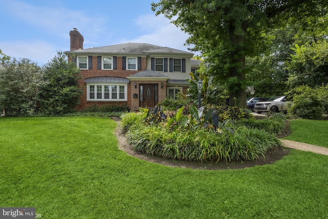 view of front facade featuring a front yard, brick siding, and a chimney