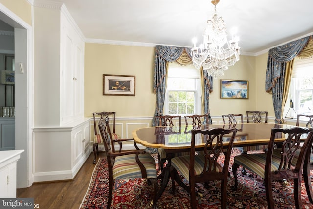 dining space with dark wood finished floors, wainscoting, ornamental molding, a decorative wall, and a notable chandelier