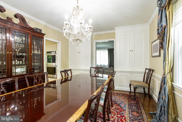 dining room featuring dark wood-type flooring, a chandelier, and ornamental molding