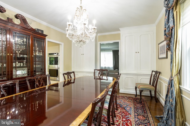 dining area featuring a notable chandelier, a decorative wall, ornamental molding, dark wood-type flooring, and wainscoting