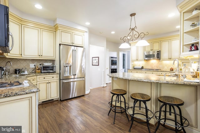 kitchen with dark hardwood / wood-style flooring, stainless steel appliances, cream cabinetry, and tasteful backsplash