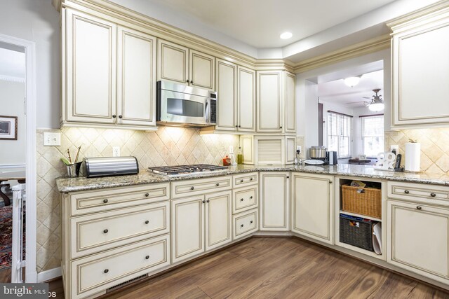 kitchen featuring cream cabinetry, appliances with stainless steel finishes, light stone counters, and dark hardwood / wood-style flooring