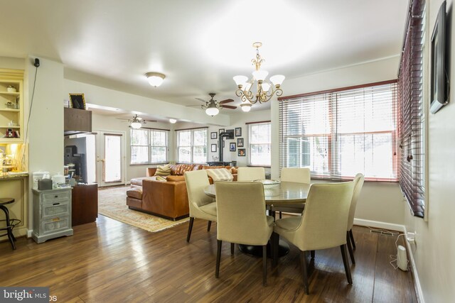 dining room featuring a healthy amount of sunlight, ceiling fan with notable chandelier, and dark hardwood / wood-style flooring