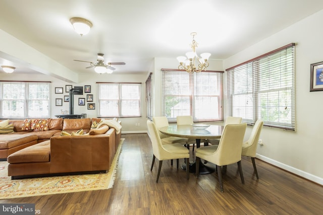 dining space featuring ceiling fan with notable chandelier, a wealth of natural light, and dark hardwood / wood-style flooring