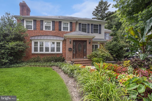 view of front of property with a chimney, a front lawn, and brick siding