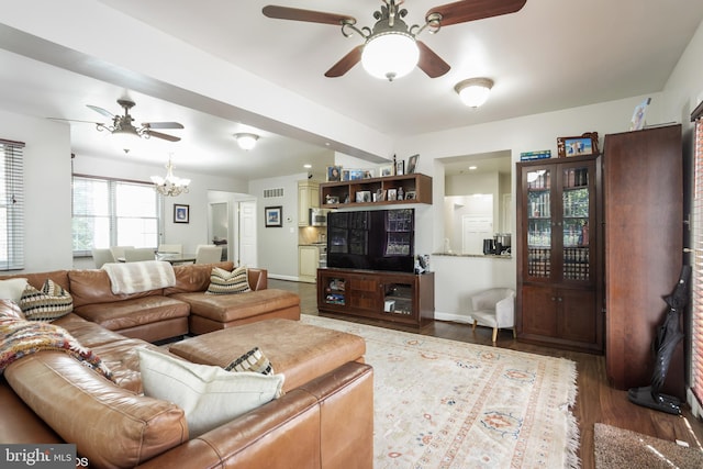 living room with ceiling fan with notable chandelier and hardwood / wood-style flooring