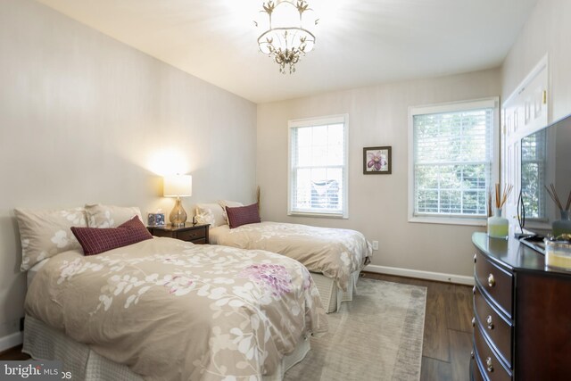 bedroom featuring a chandelier, multiple windows, and hardwood / wood-style flooring