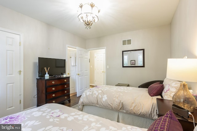 bedroom featuring an inviting chandelier, visible vents, and wood finished floors