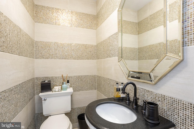 half bathroom featuring a sink, toilet, and tile walls