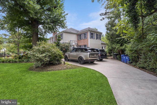 view of front of home featuring concrete driveway, brick siding, and a front lawn