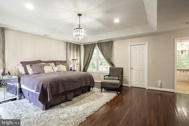 bedroom with visible vents, baseboards, dark wood finished floors, a raised ceiling, and an inviting chandelier