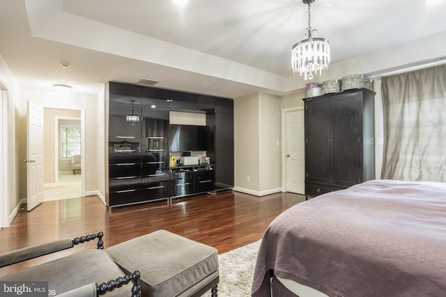 bedroom with baseboards, visible vents, dark wood finished floors, an inviting chandelier, and a tray ceiling