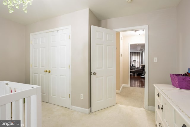 bedroom featuring a closet, light carpet, and baseboards