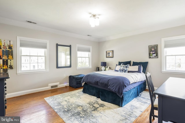 bedroom featuring wood finished floors, visible vents, and baseboards