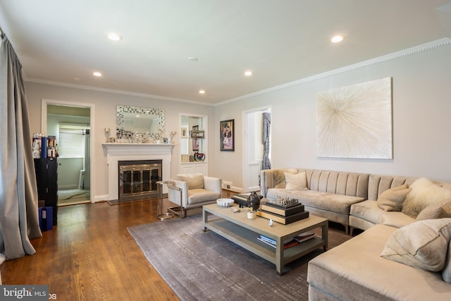 living area featuring a glass covered fireplace, recessed lighting, dark wood finished floors, and crown molding