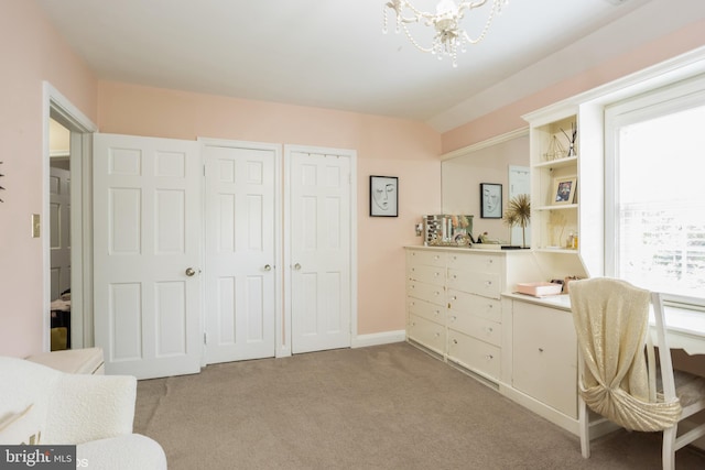 office space featuring plenty of natural light, an inviting chandelier, and light carpet