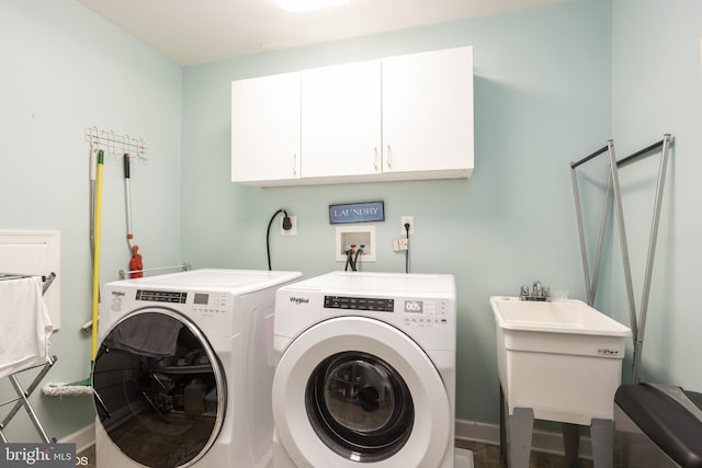 washroom featuring cabinet space, baseboards, a sink, and independent washer and dryer