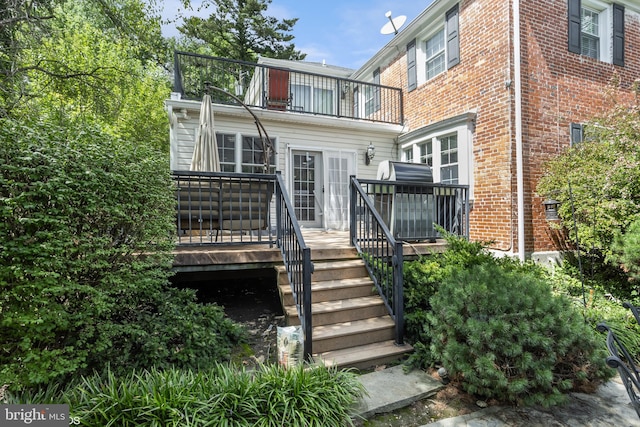 back of house featuring a deck, brick siding, and a balcony