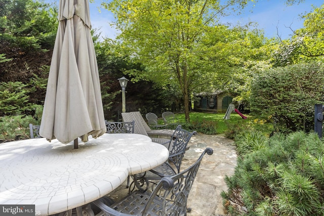 view of patio featuring outdoor dining area, an outdoor structure, and a storage unit