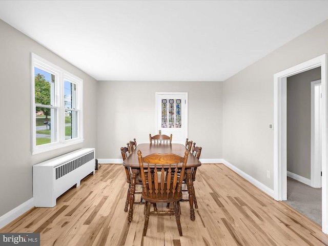 dining area featuring radiator, baseboards, and light wood finished floors