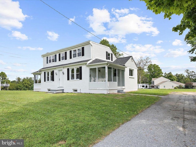 view of front of house with a sunroom and a front yard