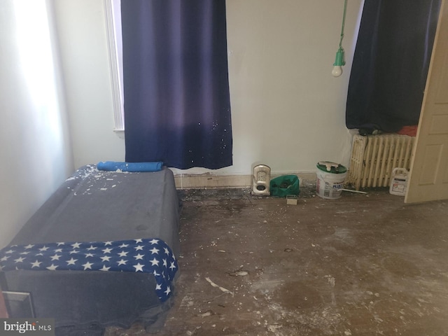 bedroom with radiator heating unit and concrete floors